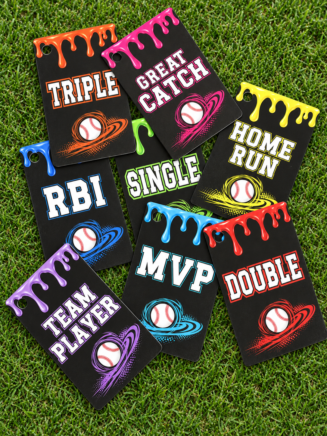 Colorful baseball achievement bag tags displayed on grass, showing the eight designs included in the 30-card starter set.