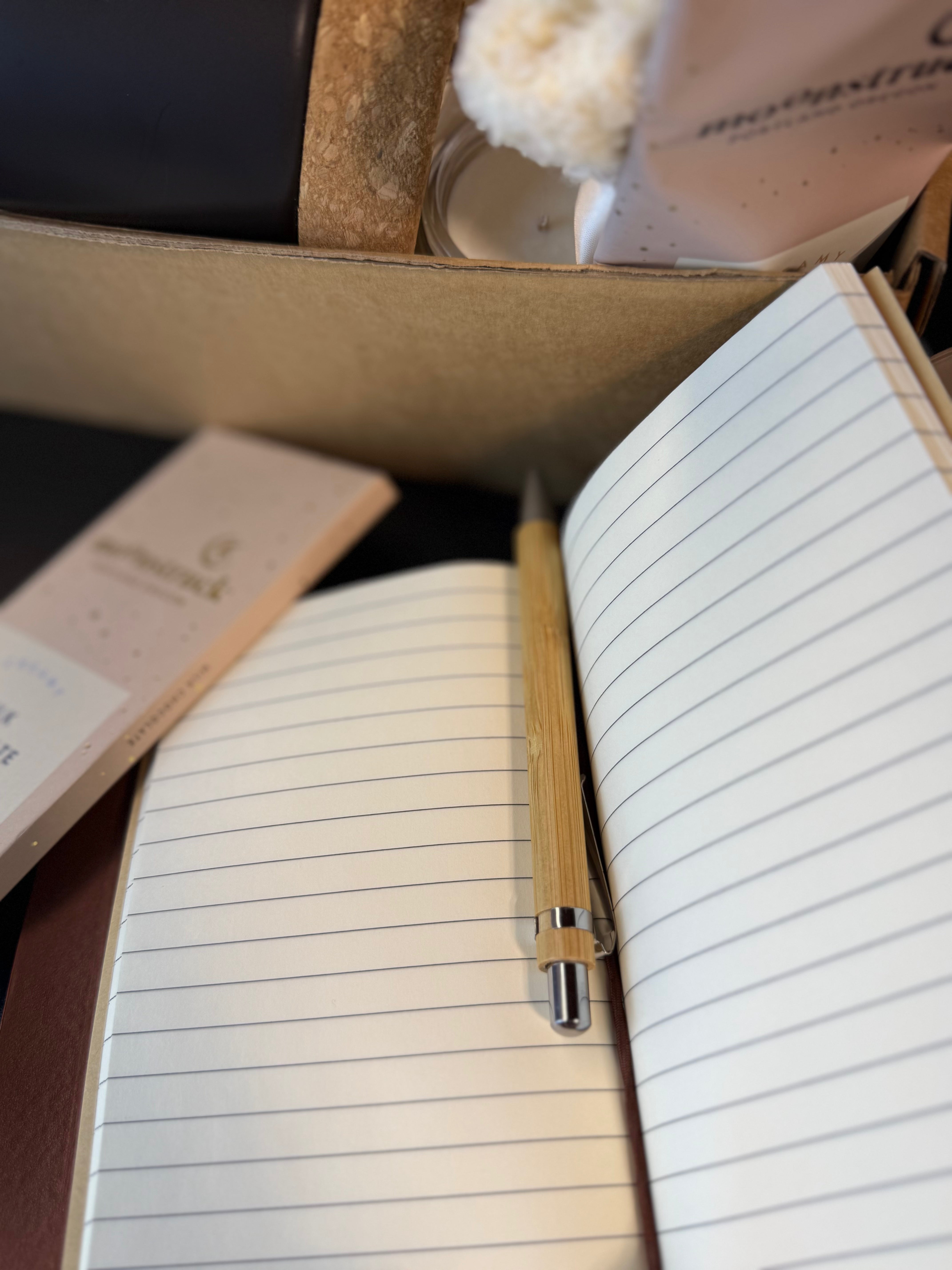 Open notebook with lined pages, pen, and small notebook on a textured surface